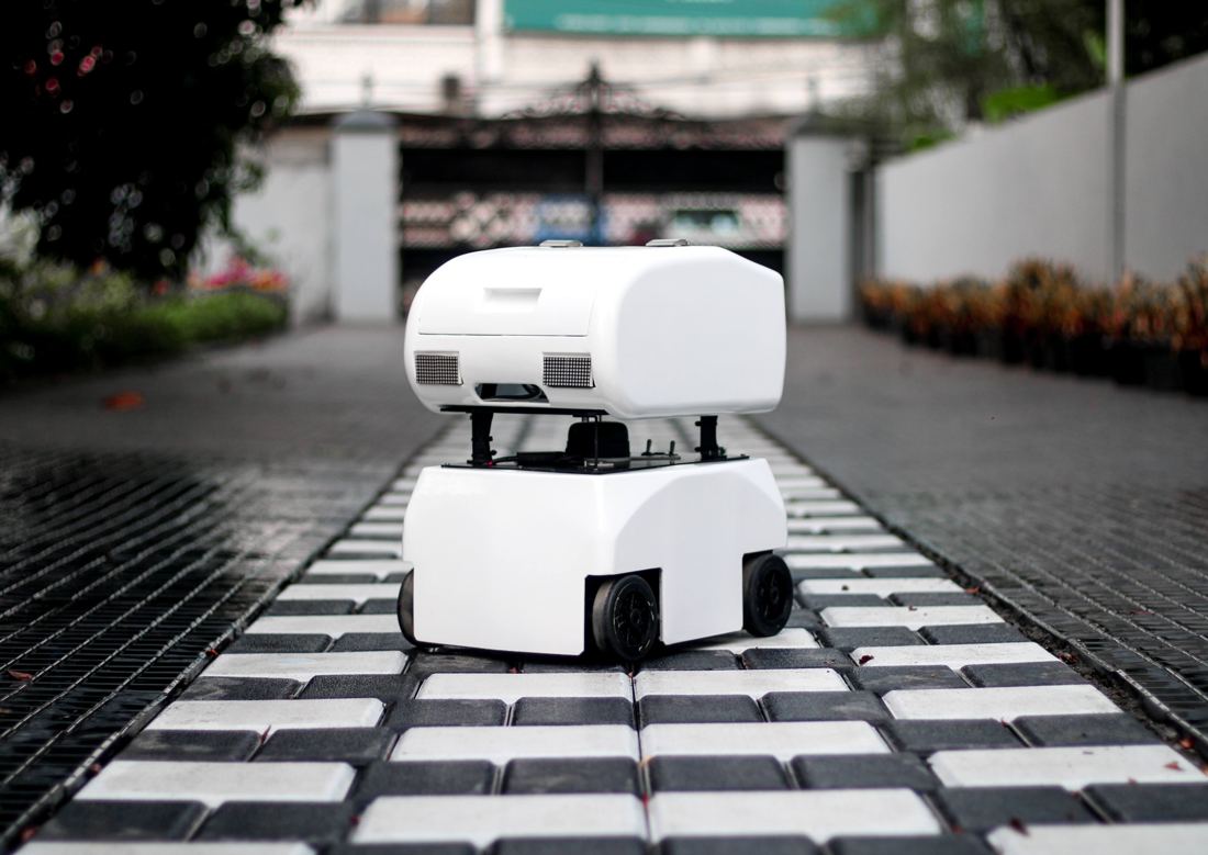 White indoor delivery robot on a tiled walkway